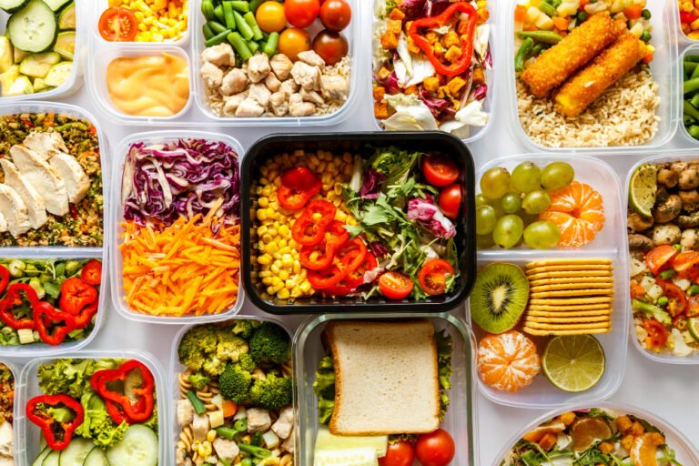 Colorful meal prep containers filled with fresh vegetables and healthy foods arranged overhead view