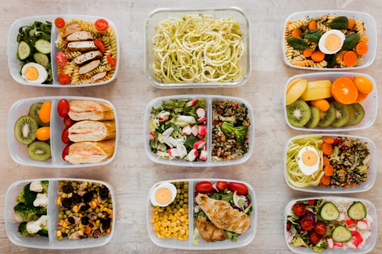 Weekly meal prep boxes arranged in a 3x3 grid featuring pasta, grilled chicken, fresh salads and fruit
